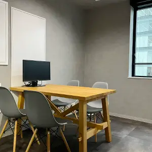 wooden desk with four chairs and a monitor