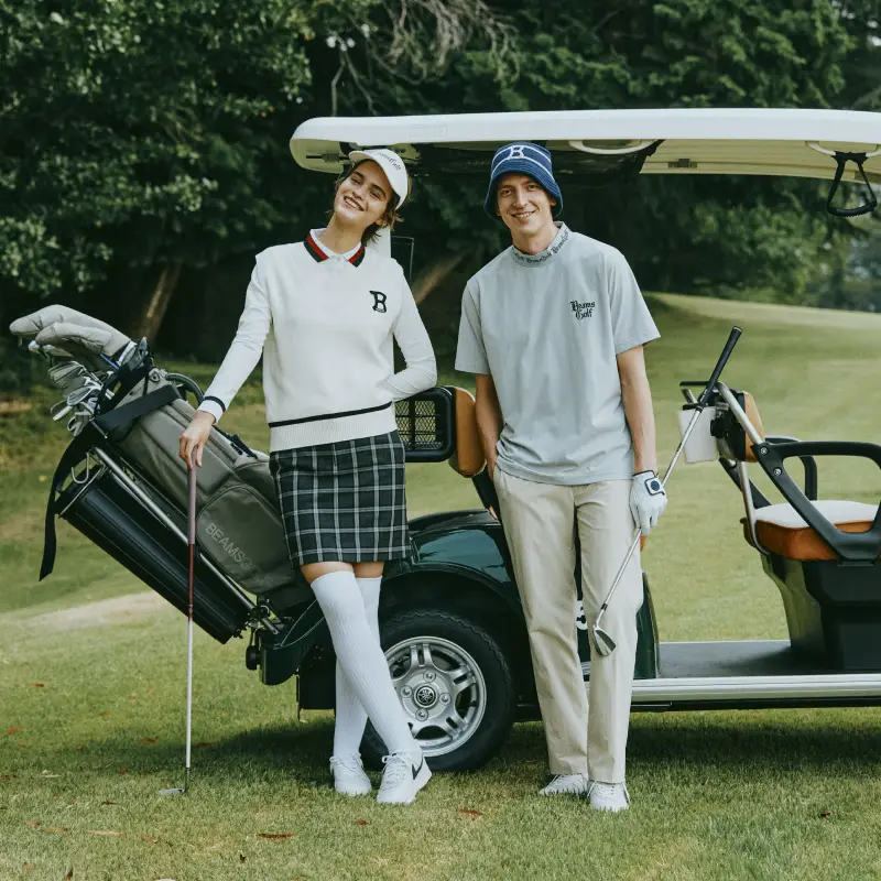 A woman and a man holding golf clubs standing in front of a golf cart
